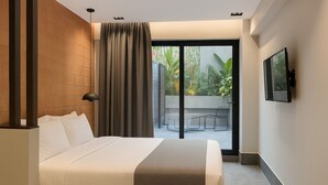 Una habitación de hotel moderna con una cama grande, un ventanal corredizo a un balcón y un televisor de pantalla plana montado en la pared.