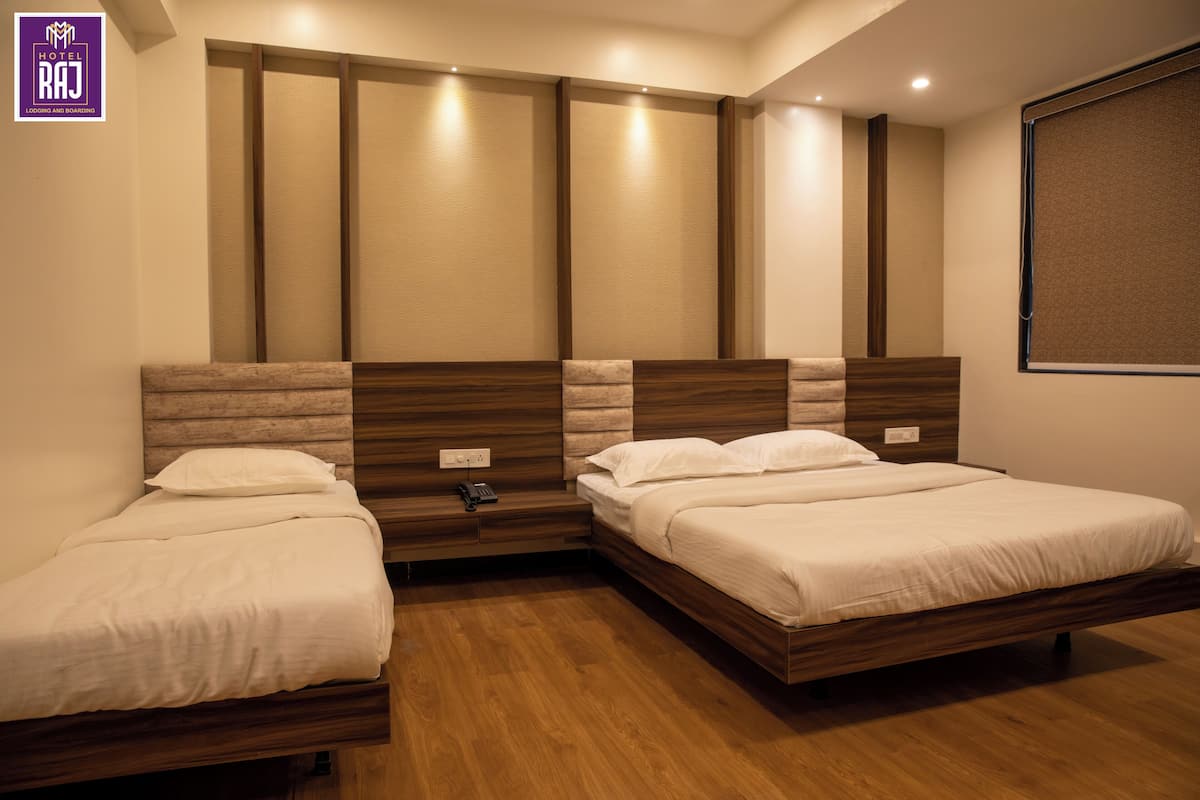 A hotel room with two beds, wooden headboards, a wall-mounted phone, and a window with blinds.
