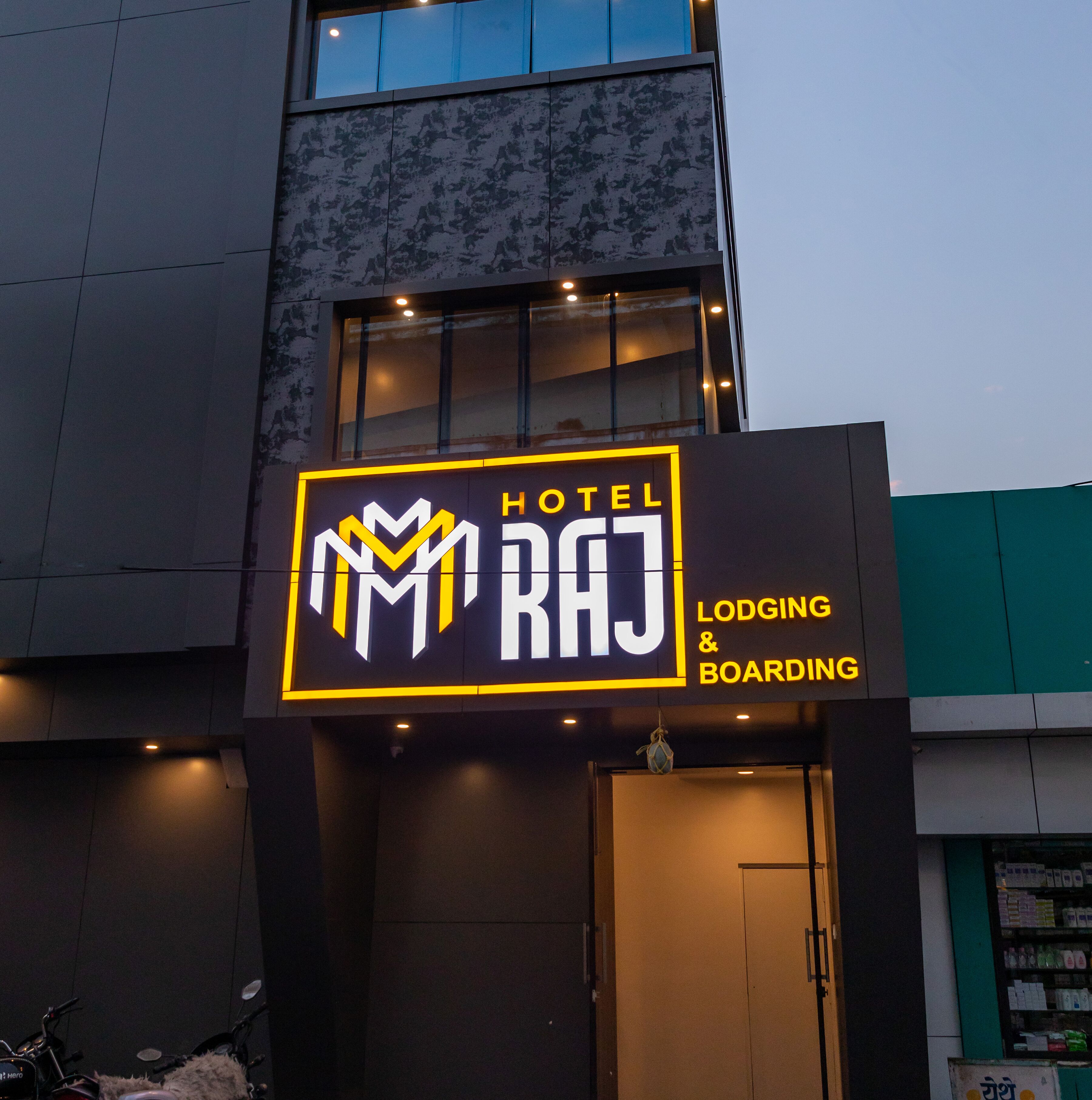 Une enseigne d’hôtel portant le nom « HÔTEL RAJ  » et indiquant « HÉBERGEMENT ET RESTAURATION ».