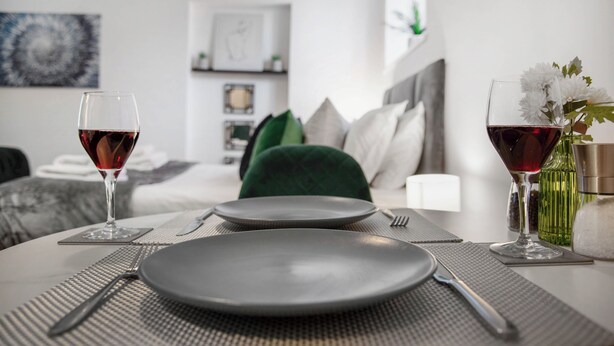 A neatly set dining table with two wine glasses, a plate, and cutlery. - WhiskAwayStays - No. 58 Studio - No. 3 (Worcester)