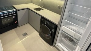 A compact kitchen with a built-in oven, a washing machine, and a refrigerator.