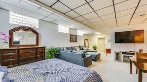 A spacious room with a large bed, a sofa, a TV, and a fireplace. - 1 Mi to Dtwn: Cozy Retreat in New Kensington! (New Kensington)