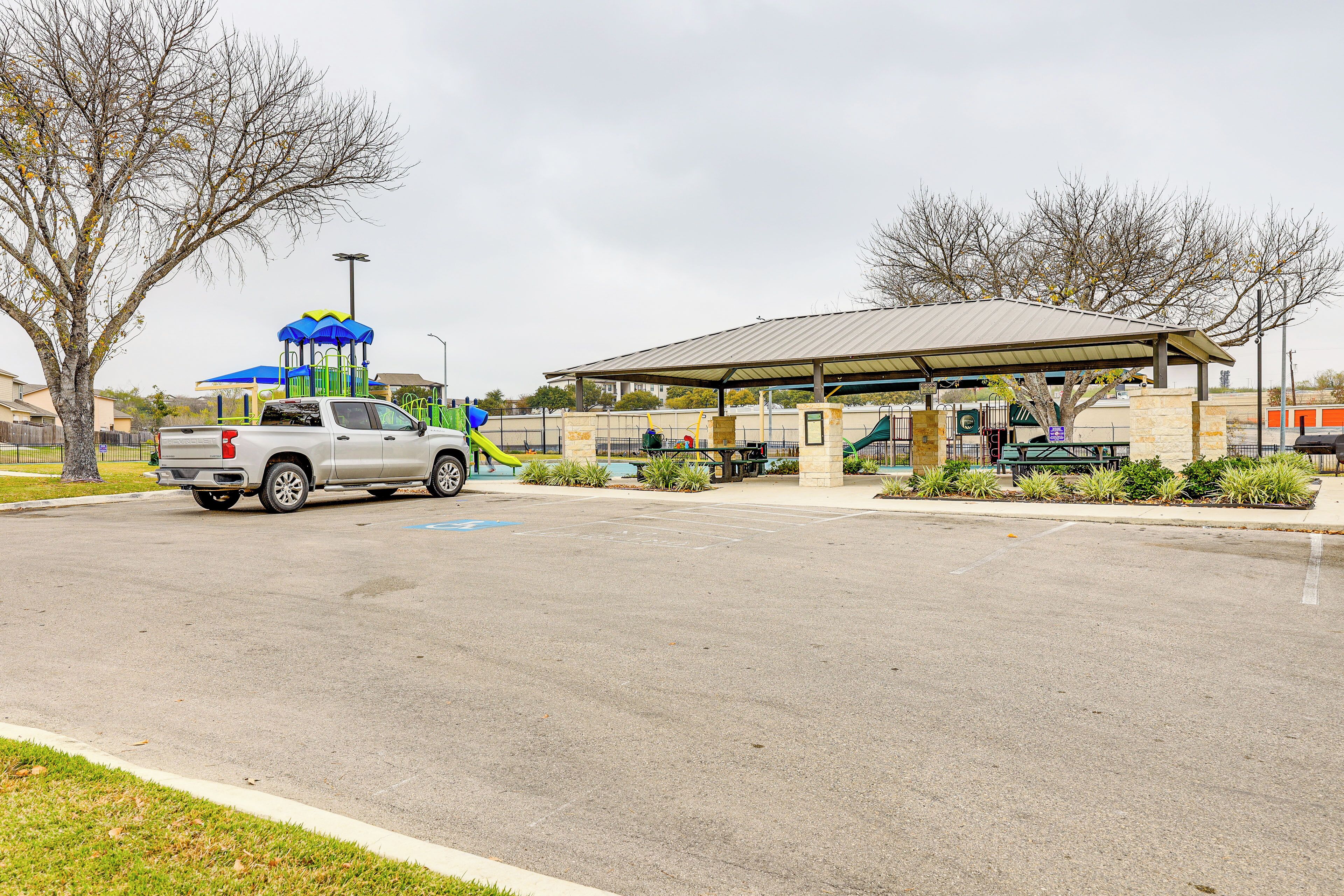 A parking lot with a playground and a covered pavilion.