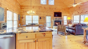Une cabane spacieuse avec un intérieur en bois, une cuisine, une cheminée et un coin salon confortable.