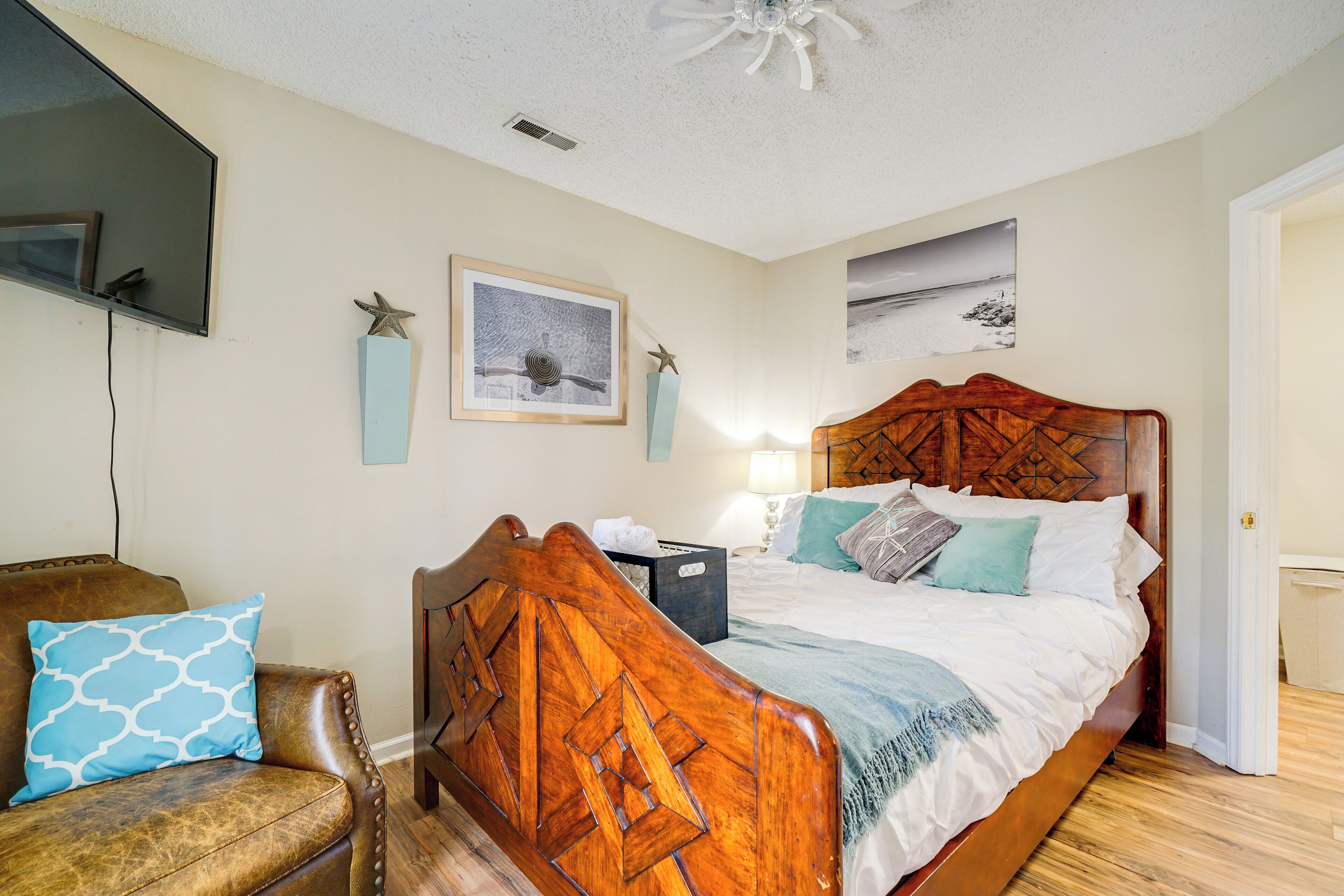 A bedroom with a wooden bed, a leather armchair, a bedside table, and wall-mounted artwork.