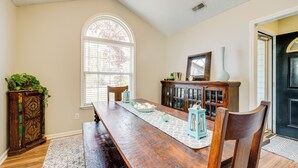 A dining room with a long wooden table, chairs, a cabinet, and a window with blinds. - Pet-friendly Home w/ Private Hot Tub in Wilmington (Wilmington)