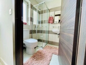 A bathroom with a toilet, shower, and sink.