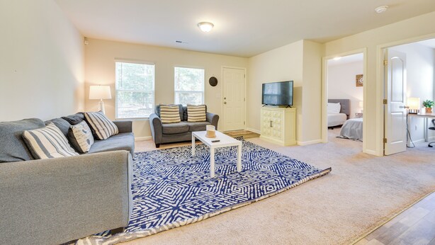 A living room with a grey sofa, a patterned rug, a white coffee table, and a TV on the wall. - 9 Mi to Shore: Family-friendly Sunset Beach Home (Sunset Beach)