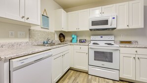 A kitchen with white cabinets, a microwave, a stove, and a dishwasher. - 9 Mi to Shore: Family-friendly Sunset Beach Home (Sunset Beach)