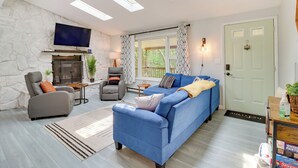 A living room with a fireplace, a sofa, a TV, and a door with a window. - Community Pools & Hot Tub: Albrightsville Cottage! (Albrightsville)