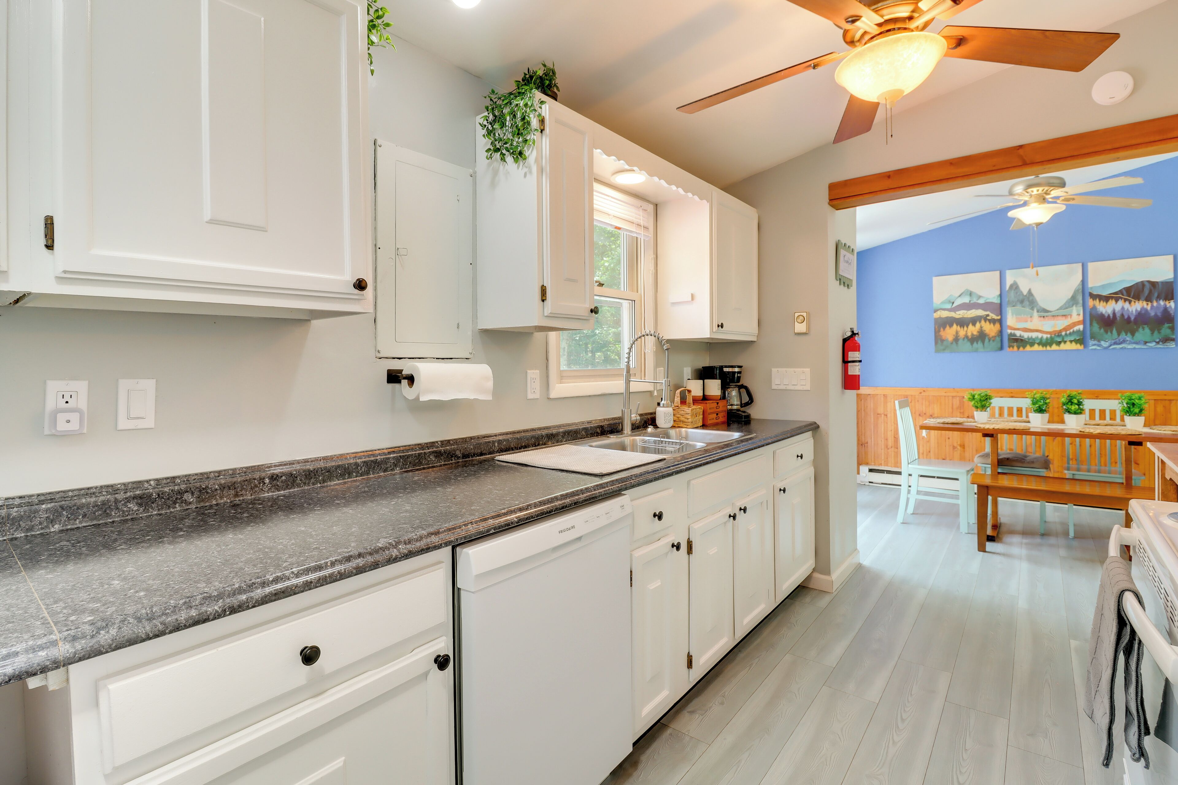 A kitchen with white cabinets, a granite countertop, and a ceiling fan.