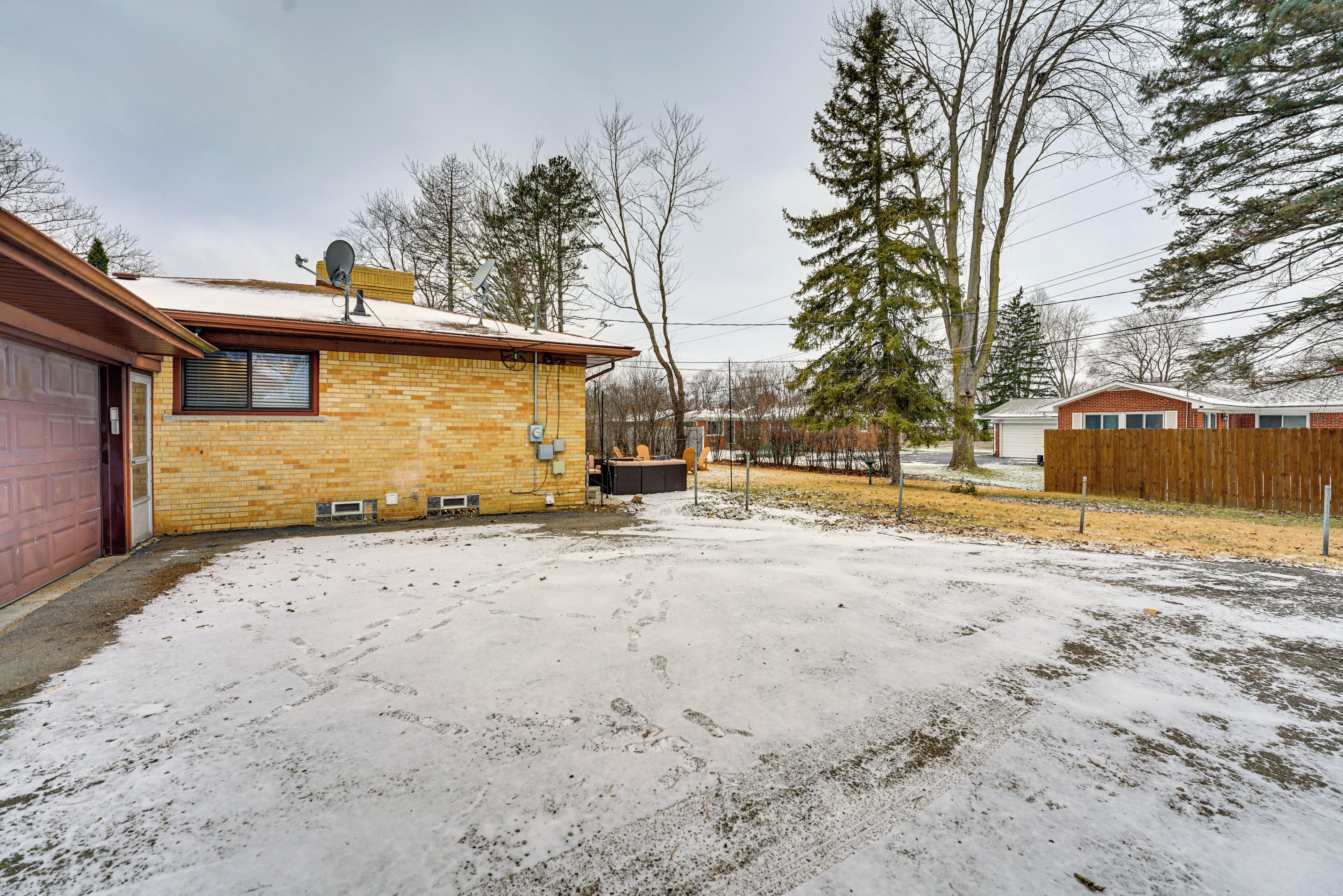A brick house with a garage, a backyard with snow, and a wooden fence.