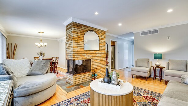 A living room with a fireplace, two sofas, a coffee table, and a patterned rug. - Fire Pit & Yard: Family Home in Farmington Hills! (Farmington Hills)