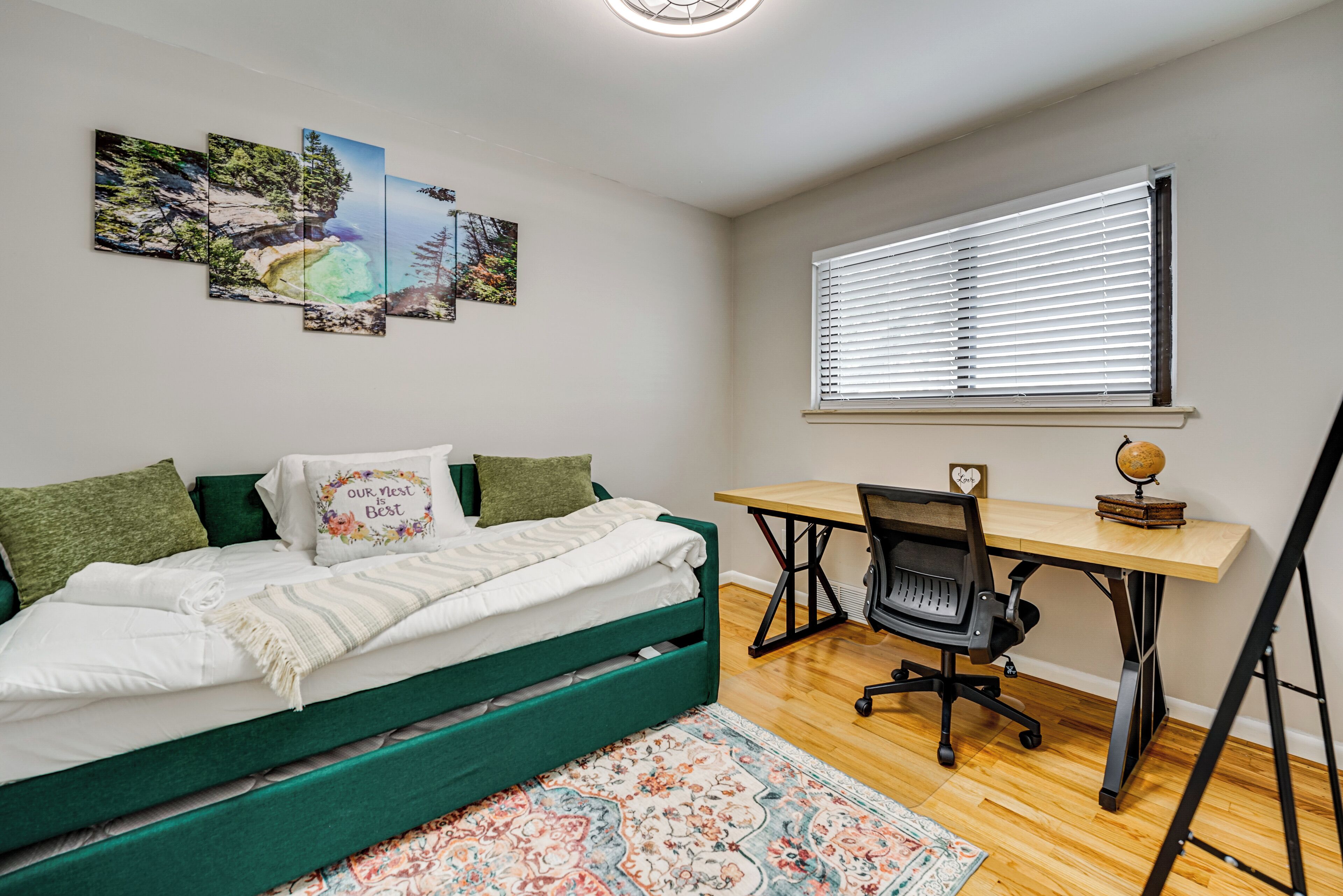 Une chambre avec un lit, un bureau et une chaise. Il y a trois tableaux accrochés au mur.