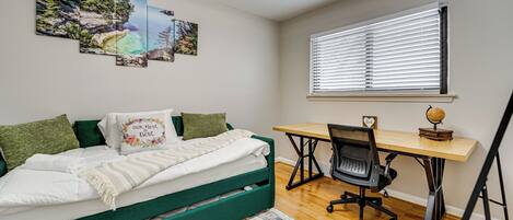 Une chambre avec un lit, un bureau et une chaise. Il y a trois tableaux accrochés au mur.