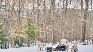 A snow-covered outdoor seating area with two chairs and a table, surrounded by trees and a snowy landscape. - Mtn-view Gem w/ Hot Tub & Fire Pit in North Conway (North Conway)