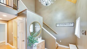 A hallway with a wooden floor, a white door, a mirror, a potted plant, a white console table, and a sign reading "CRANMORE Mountain Resort." - Mtn-view Gem w/ Hot Tub & Fire Pit in North Conway (North Conway)