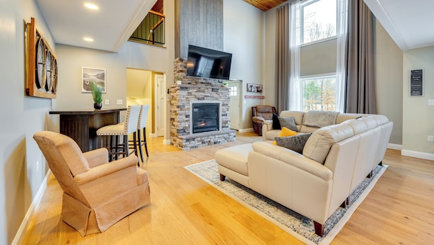 A spacious living room with a stone fireplace, a large sofa, and a dining area with a table and chairs. - Mtn-view Gem w/ Hot Tub & Fire Pit in North Conway (North Conway)