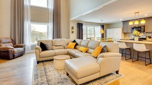 A spacious living room with a sectional sofa, a round coffee table, and a dining area with bar stools. - Mtn-view Gem w/ Hot Tub & Fire Pit in North Conway (North Conway)