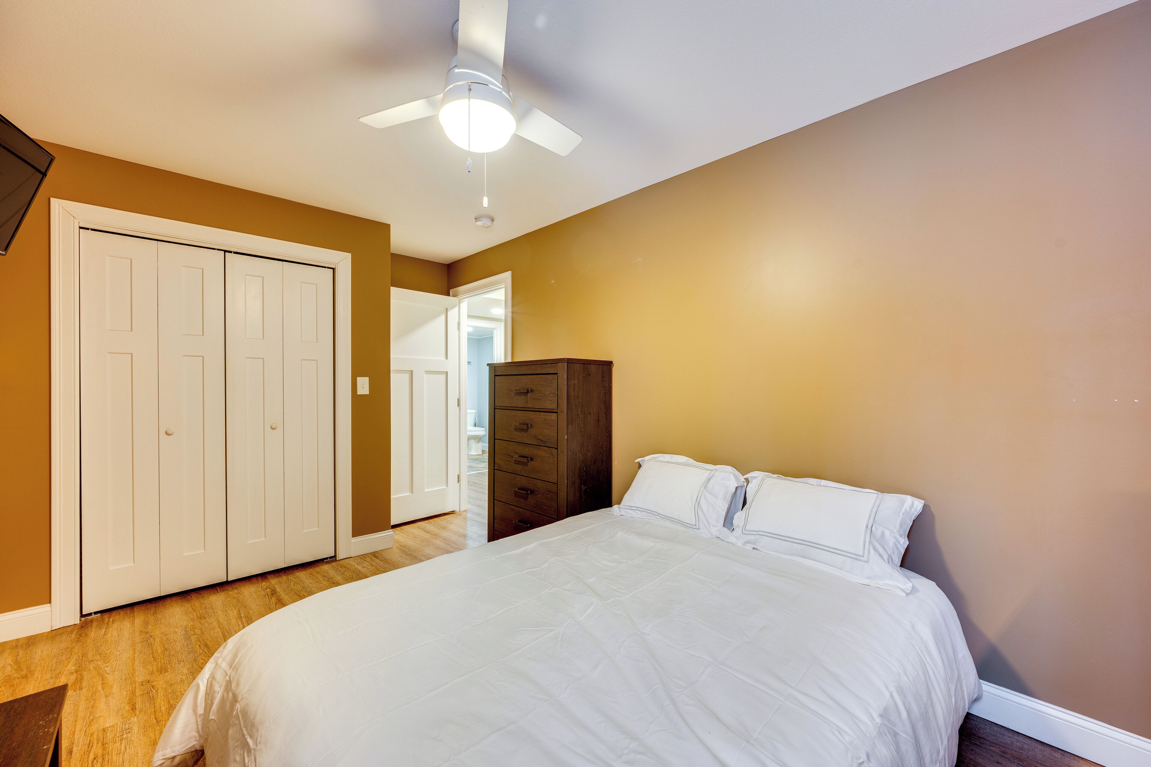 A bedroom with a bed, a wardrobe, and a ceiling fan.