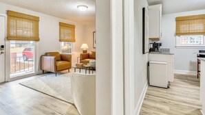Ein modernes Wohnzimmer mit Sofa, Couchtisch und Lampe, verbunden mit einer Küche inklusive Kühlschrank und Herd.