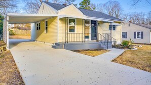 Ein einstöckiges Haus mit überdachter Veranda, Vorgarten und Auffahrt.