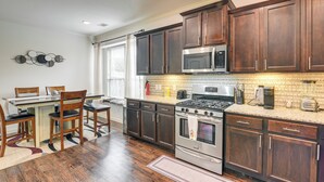 Una cocina con armarios de madera, electrodomésticos de acero inoxidable y una zona de comedor con sillas.