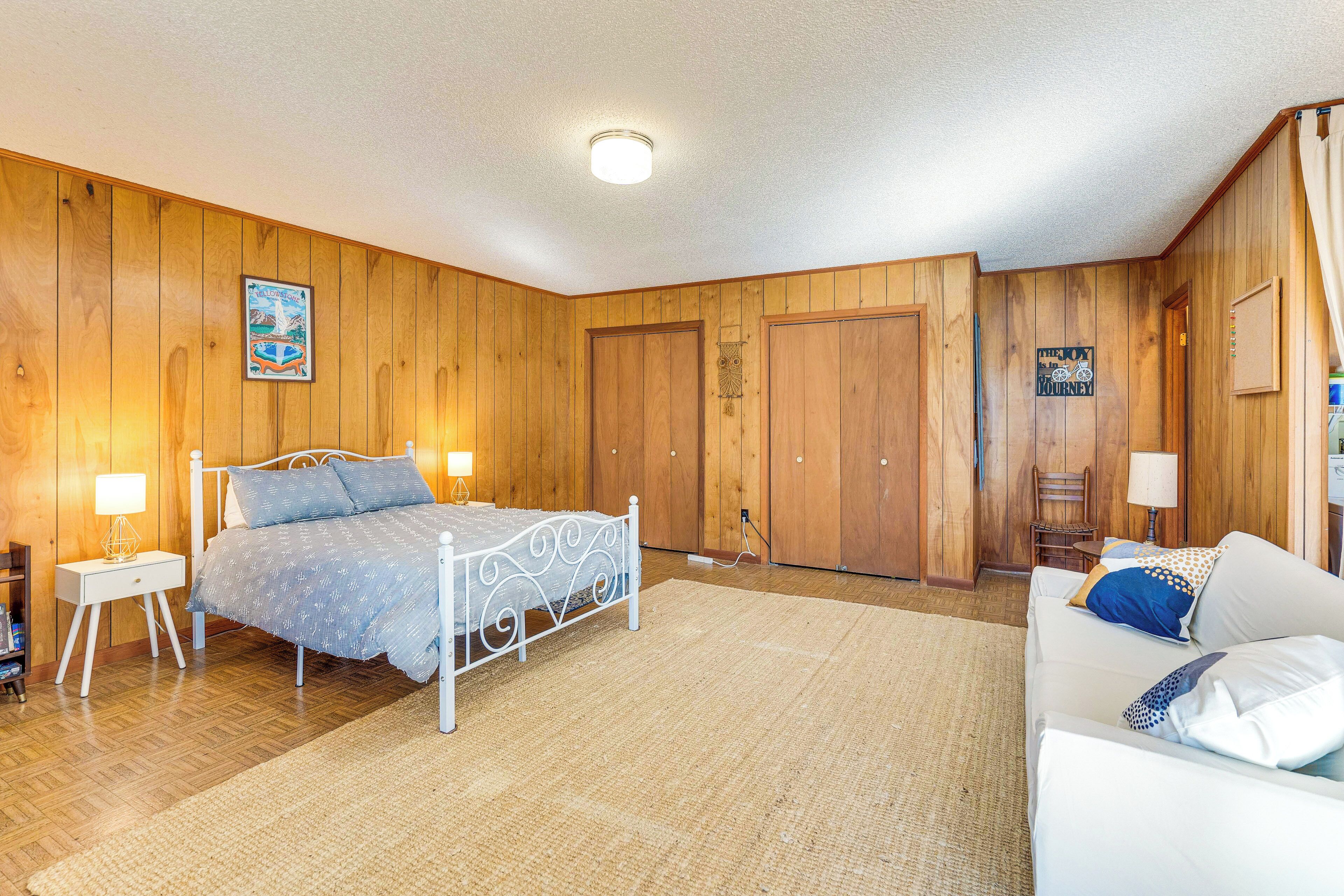 A bedroom with a metal bed frame, wooden walls, a white ceiling, and a wooden floor.