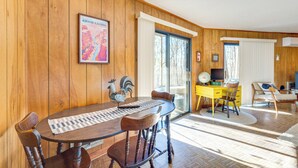 A wooden-paneled room with a dining table, chairs, a yellow desk, and a large window. - Hot Tub, Deck & Fire Pit: Secluded Cabin in Murphy (Murphy)
