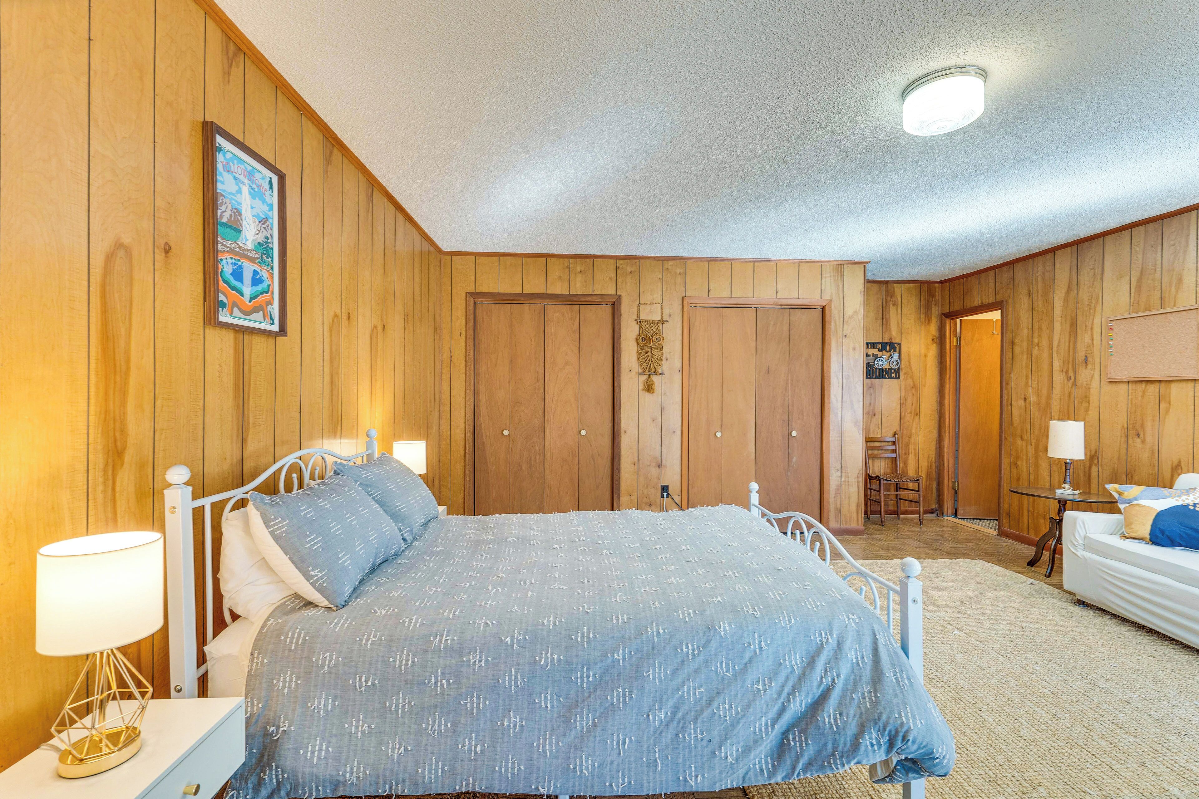 A bedroom with a bed, nightstands, a chair, and a table.