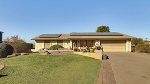 Une maison de plain-pied avec un garage, une pelouse bien entretenue et des panneaux solaires sur le toit.
