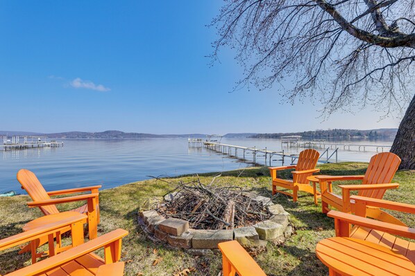 Un espace de détente aménagé au bord du lac, avec des chaises en bois et un foyer.