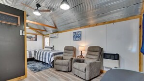 Una habitación acogedora con una cama, dos sillones reclinables, un escritorio y un cartel que dice 'Welcome'.