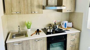 A kitchen with wooden cabinets, a stainless steel sink, a stove, and a toaster. - FL3 Birgu Center 2BR Apartment (Birgu)