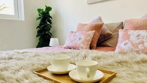 A bed with a fluffy white cover, two white cups on a tray, and a plant in the background. - FL3 Birgu Center 2BR Apartment (Birgu)