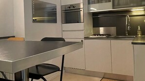 A modern kitchen with white cabinets, a stainless steel oven, and a black countertop.