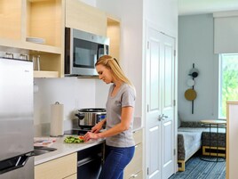 A modern kitchen with a microwave, stove, and a person preparing food.