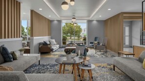 Een moderne hotellobby met een zithoek, een receptiebalie en grote ramen met uitzicht op het omliggende landschap.