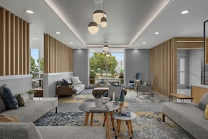 A modern hotel lobby with a seating area, a reception desk, and large windows offering a view of the outdoors. - Towneplace Suites By Marriott Nampa (Nampa)