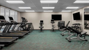 Une salle de sport équipée de tapis de course, de vélos elliptiques et de matériel de musculation.