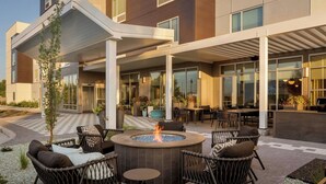 A modern outdoor seating area with wicker chairs, a central fire feature, and a covered patio. - Towneplace Suites By Marriott Nampa (Nampa)