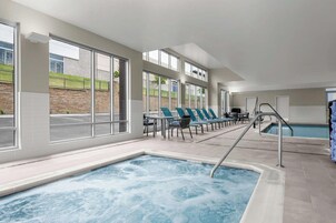Una piscina interior moderna con ventanales amplios, sillas de descanso y una zona de borde de piscina.