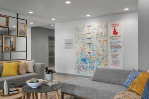 A modern living room with a grey sofa, a coffee table, and a decorative wall piece.