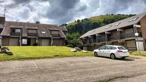 Edifício residencial com um carro estacionado em frente.
