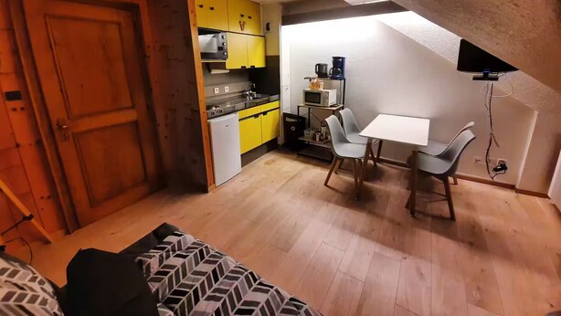 Um espaço compacto com cozinha compacta, área de refeições e sofá.