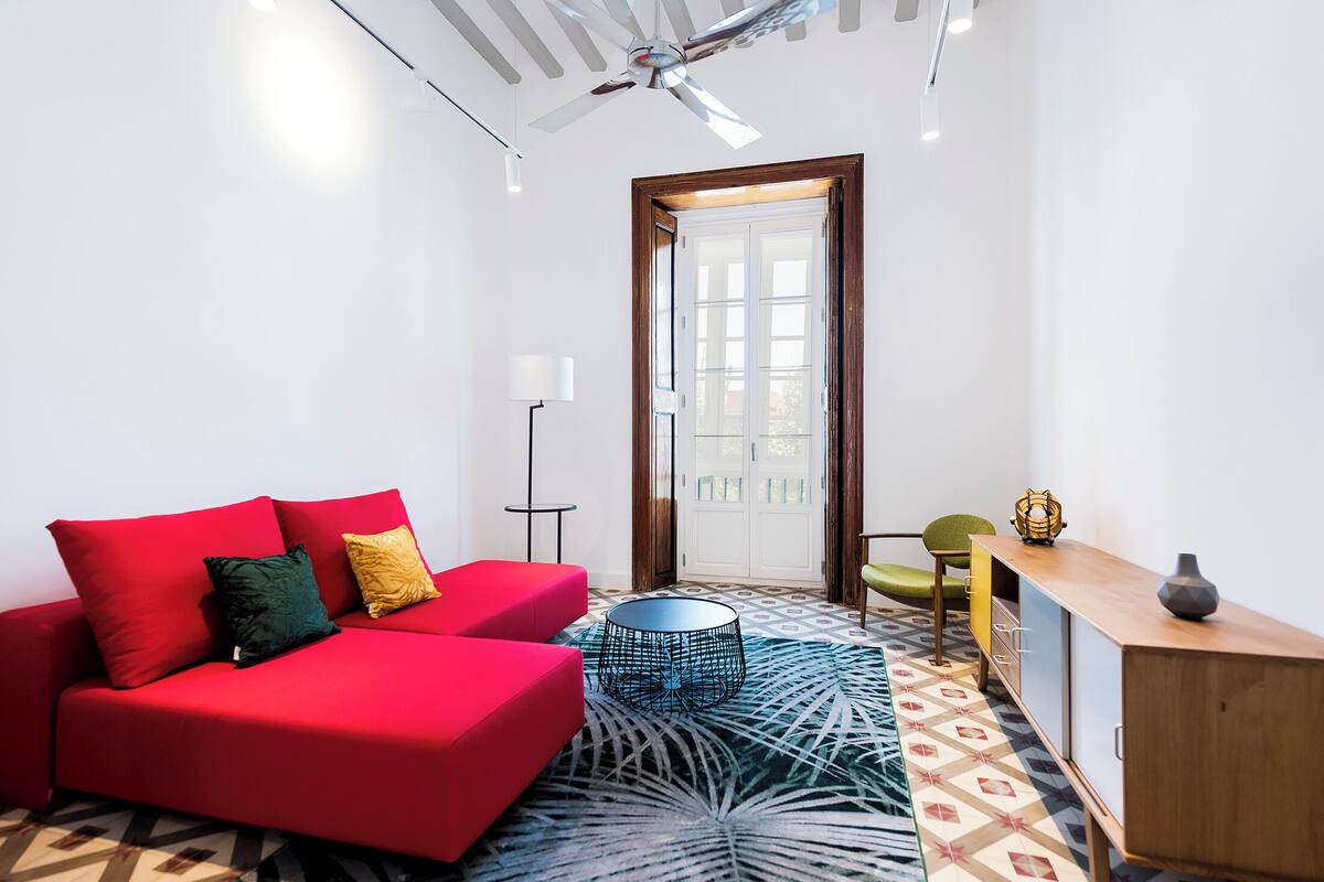 A modern living room with a red sofa, a round coffee table, and a patterned rug.