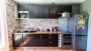 A modern kitchen with dark cabinets, a stone backsplash, and a stainless steel refrigerator. - Apartment Les Roses du Vercors Panoramic view (Villard-de-Lans)