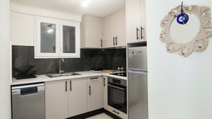 Une cuisine moderne dotée d’appareils électroménagers en acier inoxydable, de meubles blancs et d’un plan de travail noir.