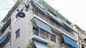 Un immeuble à plusieurs étages doté de balcons, une voiture garée devant, et un bâtiment recouvert de graffitis.