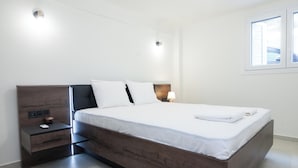 Une chambre moderne avec un grand lit, une table de chevet avec une lampe et une fenêtre avec des stores.